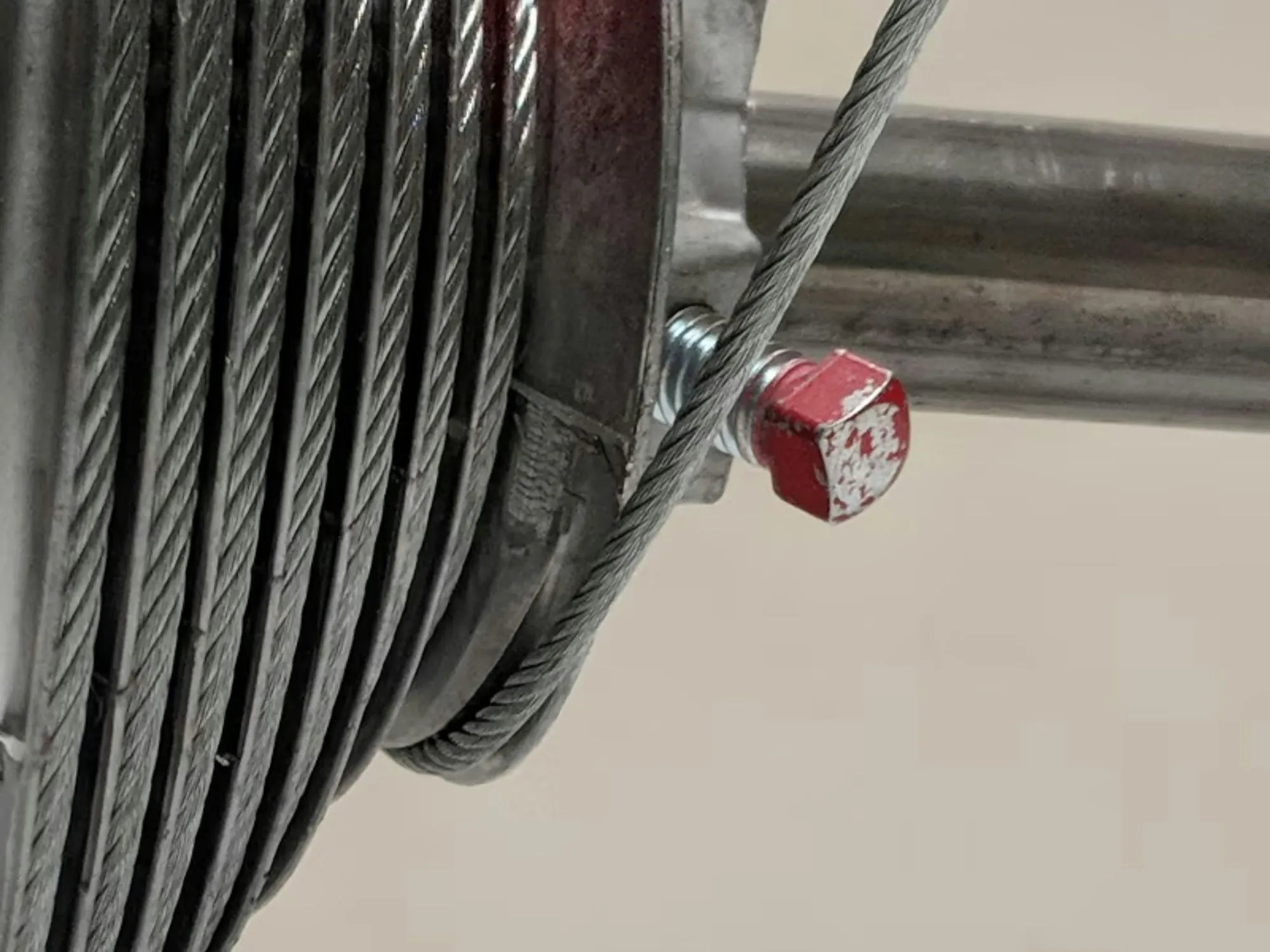 Close-up of a garage door spring shaft and lift cable drum